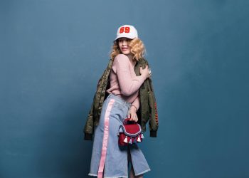 Fashion portrait of a young woman with a stylish denim outfit, cool jacket, and a vibrant cap.