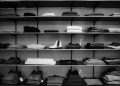 Neatly folded clothing and shoes displayed on shelves in a boutique setting.