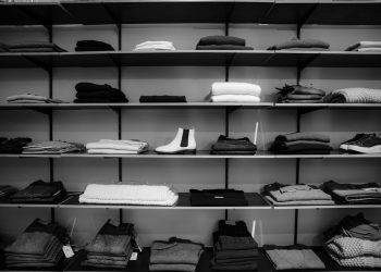Neatly folded clothing and shoes displayed on shelves in a boutique setting.