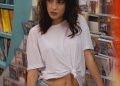 Fashionable woman posing in a music store wearing a white t-shirt and jeans.