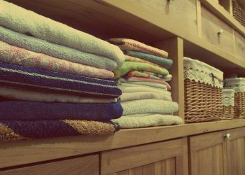 Tidy wooden cabinet with neatly stacked towels and decorative baskets in an indoor setting.