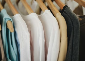 A selection of colorful clothes neatly hanging on wooden hangers in a retail store.