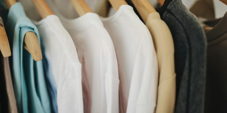 A selection of colorful clothes neatly hanging on wooden hangers in a retail store.