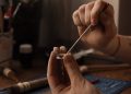 Close-up of a jeweler crafting handmade jewelry on a workbench using tools and silver.