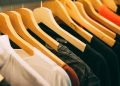A close-up view of a row of clothes on wooden hangers, showcasing various fabrics and colors in a wardrobe setting.